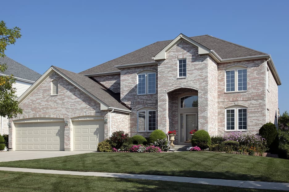 Modern brick house with a manicured lawn, symbolizing homeownership goals.